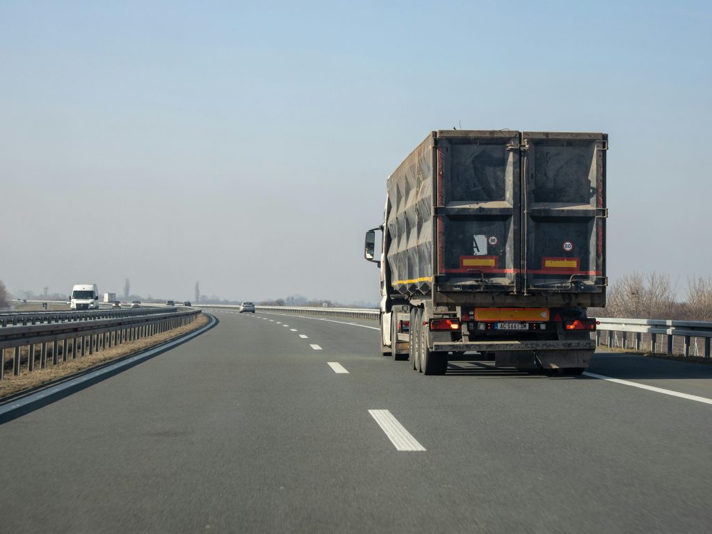 A cargo truck travels down an empty highway on a clear day, showcasing transportation and logistics.