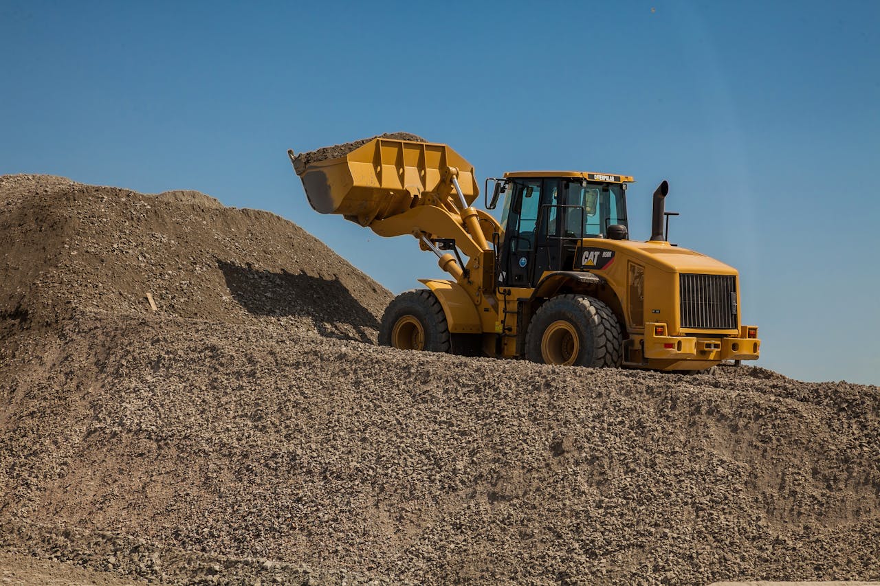A large wheel loader moving gravel at an outdoor construction site.